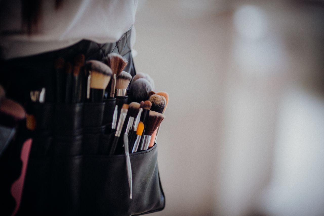 Close-up of a collection of professional makeup brushes in a belt, ready for use.