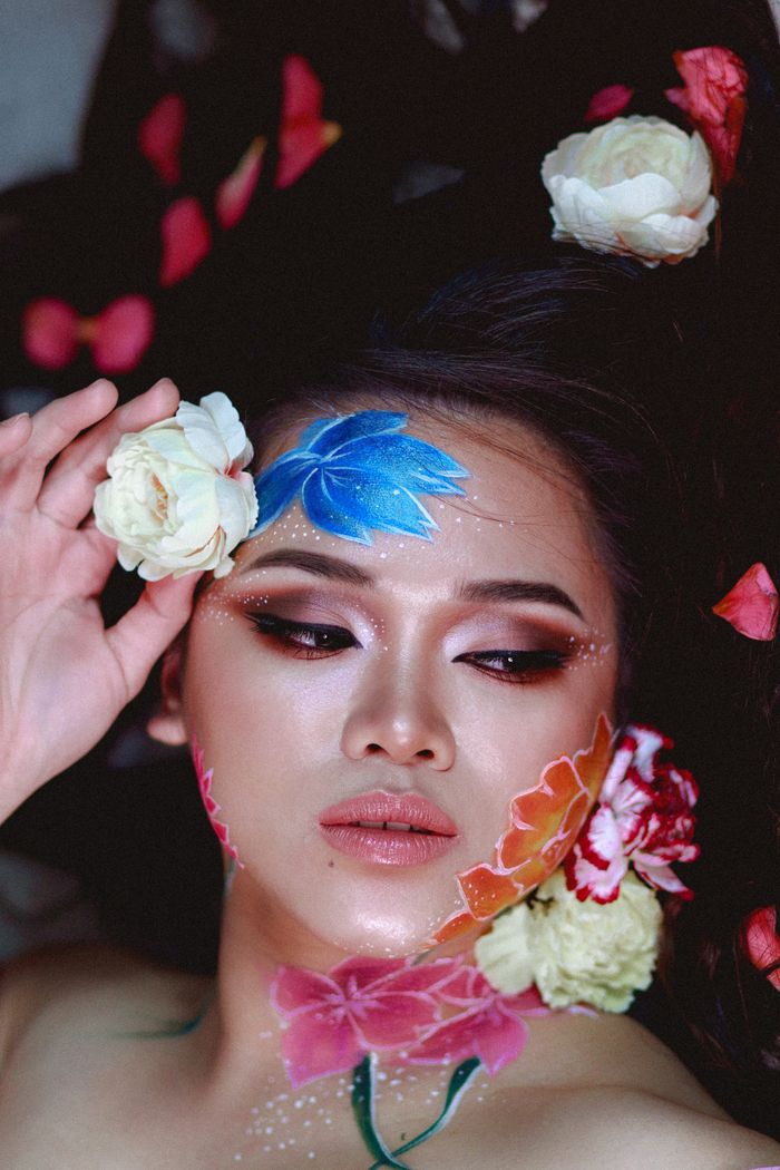 Artistic portrait featuring a woman with colorful floral makeup, embodying creativity and beauty.